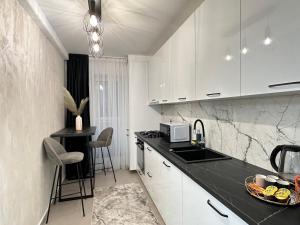 a kitchen with white cabinets and a black counter top at Urban Luxury Accomodation - Cozy Apartments at Coresi Mall #Brasov in Braşov