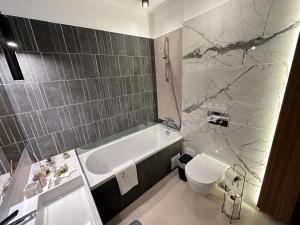a bathroom with a tub and a toilet and a sink at Urban Luxury Flats - Cozy Apartments at Coresi Mall #Brasov in Braşov +33 photos