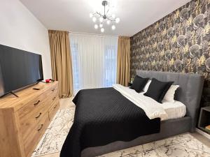 a bedroom with a bed and a flat screen tv at Urban Luxury Accomodation - Cozy Apartments at Coresi Mall #Brasov in Braşov