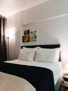 um quarto com uma cama grande com lençóis brancos e almofadas em Bebel 1108 em Florianópolis