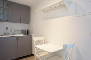 una cocina con armarios blancos y una mesa y sillas blancas. en Studio Romantique à Saint Zacharie, en Saint-Zacharie