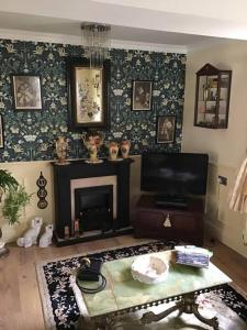 a living room with a fireplace and a tv at The Miners Cottage in Blackwood