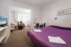une chambre d'hôtel avec un lit violet et une télévision dans l'établissement Pensjonat Wojciech, à Władysławowo