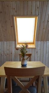 a wooden table with a vase on it with a window at Villa standard n'Bjeshkë in Dragash
