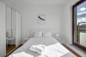 een witte slaapkamer met een wit bed en een raam bij 1Br New Apt 20Min centre in Warschau
