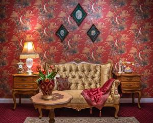 a living room with a couch and a red wall at Rezydencja Grawert Boutique & Spa in Lądek-Zdrój