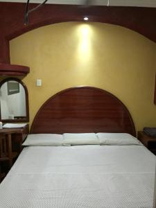a bed with a wooden headboard in a room at Hotel Xalapa in Veracruz