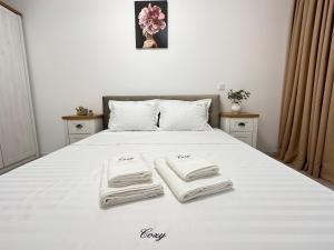 un letto bianco con tre asciugamani sopra di Cozy Luxury Apartments - Coresi Mall #Brasov a Braşov