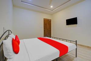 1 dormitorio con 1 cama con almohadas rojas y TV en OYO Flagship Hotel Vathsalya, en Warangal