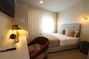 a hotel room with a bed and a desk with a lamp at Hotel America in Porto