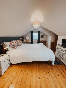 um quarto com uma grande cama branca e pisos em madeira em Dunard house. em Tullaha