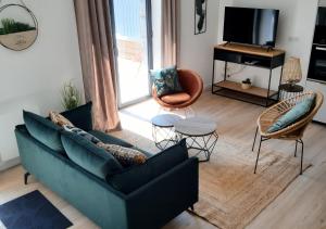 een woonkamer met een bank, stoelen en een televisie bij Les Chaumines, St Cast le Guildo in Saint-Cast-le-Guildo