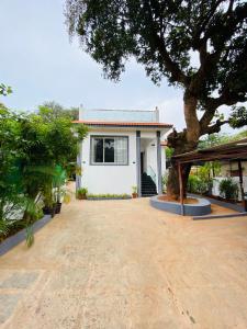 a white house with a tree in front of it at Laxmi Villa 3BHK Premium Villa with terrace Anjuna in Anjuna