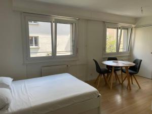 ein Schlafzimmer mit einem Bett, einem Tisch und zwei Fenstern in der Unterkunft Studio proche de la gare ! in Lausanne