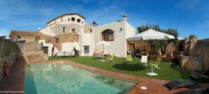 une villa avec une piscine en face d'une maison dans l'établissement Mas Llagostera, à Bisbal del Penedès