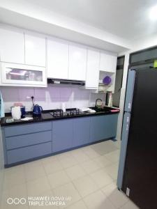 une cuisine avec des armoires blanches et des comptoirs bleus dans l'établissement KASTURI GUEST HOUSE PUTRAJAYA, à Putrajaya