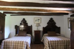 two beds in a room with wooden ceilings at Cal Marques in Santa Oliva