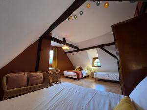 a attic room with a bed and a couch and a chair at Gîte Trotthus maison familiale avec piscine in Hunawihr