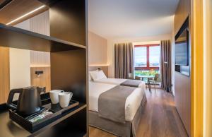 パンプローナにあるOccidental Pamplonaのベッド付きのホテルルームと景色を望む客室を提供しています。