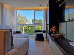 a living room with a couch and a fireplace at Residencial Toscano 2 Suítes by Achei Gramado in Gramado
