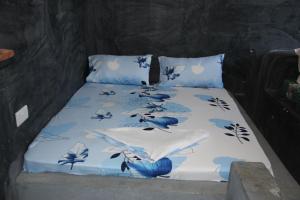 a bed with blue and white sheets and pillows at Mbuyuni Lodge Nungwi in Nungwi