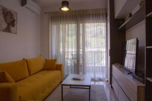 a living room with a yellow couch and a tv at Yellow Studio Retreat Tivat in Tivat