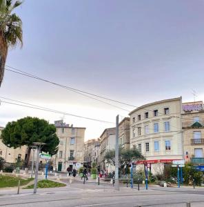 uma rua urbana vazia com edifícios e palmeiras em Grand studio de charme au cœur de Montpellier et Wifi em Montpellier