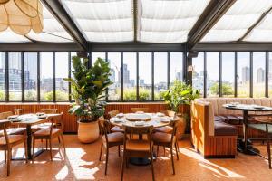 a restaurant with tables and chairs and windows at The Hoxton, Shoreditch in London