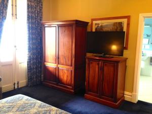 a bedroom with a tv and a large wooden cabinet at The York Palace Accommodation in York