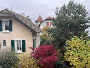 una casa con ventanas verdes con persianas y árboles en Proche Lausanne: Studio bien équipé, en Prilly