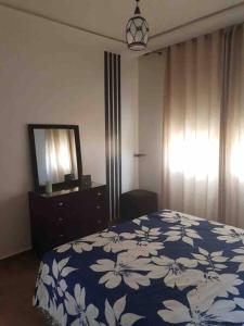 Schlafzimmer mit einem Bett, einer Kommode und einem Spiegel in der Unterkunft Appartement Wynwood 2 in Oujda