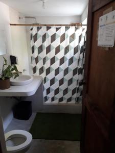 a bathroom with a toilet and a checkered shower curtain at Backpackers Hostel in Sipacate