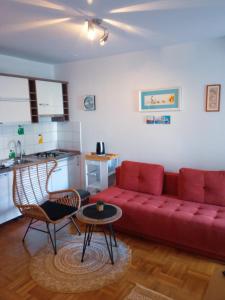 Il comprend un salon avec un canapé rouge et une cuisine. dans l'établissement Apartman Vesna 4 persons, à Njivice