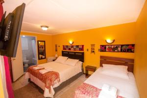 two beds in a room with yellow walls at Hostal Kirckir in San Pedro de Atacama