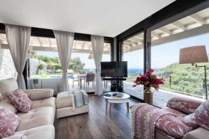 a living room with a couch and a tv and large windows at Lujo con piscina climatizada,jacuzzi,playa privada in Tossa de Mar