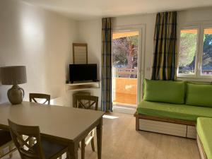 uma sala de estar com um sofá verde e uma mesa em Domaine Valescure Appartement 1 ou 2 pieces vue jardin ou piscine em Saint-Raphaël