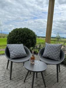 2 sillas con almohadas y una botella en una mesa en Suite Retreat Luxury Apartment, en Penruddock