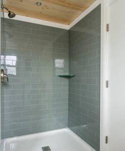 een badkamer met een bad en een douche met groene tegels bij Allure Muskoka Houseboat in Huntsville