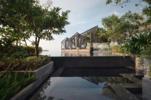 an external view of a glass house with trees at Edge Central Pattaya by JJJ in Pattaya