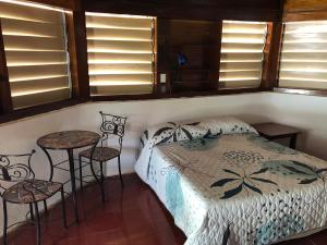 a bedroom with a bed and two chairs and windows at Costa De Cocos in Xcalak