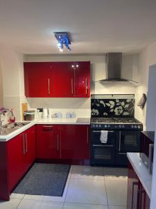 a kitchen with red cabinets and a black stove at Spare room in a family house in Bristol