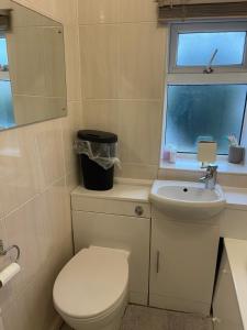 baño con aseo y lavabo y ventana en Spare room in a family house, en Bristol