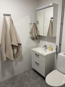 Baño blanco con lavabo y espejo en Näsijärvi lakeview apartment en Tampere