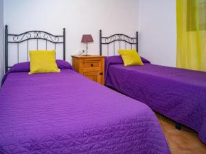 2 camas en una habitación con sábanas moradas y almohadas amarillas en Casa con Terraza Privada cerca del Pueblo para familias A, en Conil de la Frontera