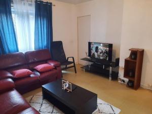 sala de estar con sofá y TV en Chambre meublée, en Poissy