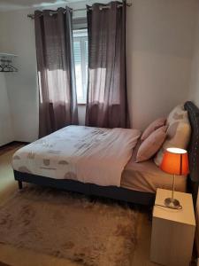 1 dormitorio con 1 cama con cortinas y lámpara en Chambre meublée, en Poissy