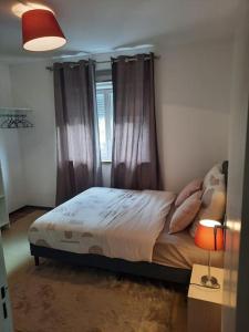 1 dormitorio con 1 cama con cortinas y ventana en Chambre meublée, en Poissy