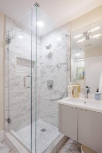 baño blanco con ducha y lavamanos en Artist Gallery Downtown 2Bed 2Bath Condo en Cincinnati