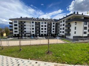 two trees in the grass in front of a building at Zeus apartman in Banja Luka