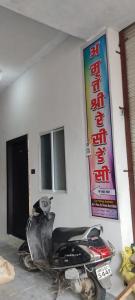 una motocicleta estacionada junto a una pared con un cartel en Hotel Amrit shree, en Ujjain